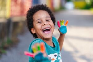 Child smiles with painted hands.