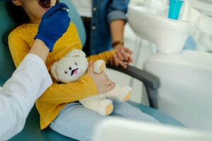 Child holding a teddy bear at the dentist for an extraction